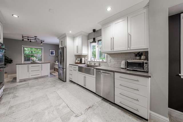 18005 Lisa Ln, Brookfield, WI 53045 - kitchen with appliances with stainless steel finishes, a sink, baseboards, backsplash, and dark countertops