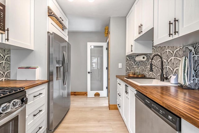 405 W Washington St, Waterford, WI 53185 - kitchen with wood counters, stainless steel appliances, light wood-style flooring, tasteful backsplash, and white cabinets