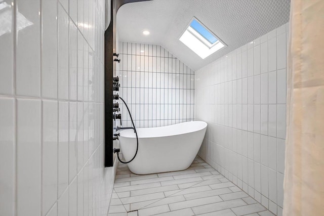 405 W Washington St, Waterford, WI 53185 - bathroom with tile walls, a freestanding tub, lofted ceiling, a skylight, and tile patterned flooring