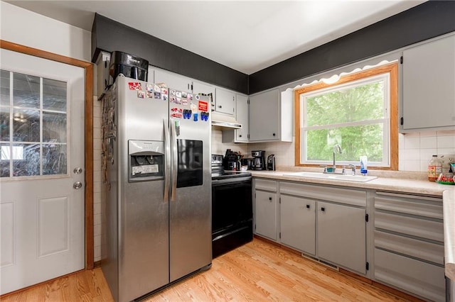 5603 170th St, Chippewa Falls, WI 54729 - kitchen featuring stainless steel fridge with ice dispenser, black electric range oven, a sink, light wood finished floors, and decorative backsplash