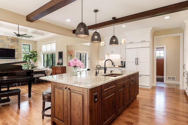 1102 Eldon Way, Edgerton, WI 53534 - kitchen featuring paneled built in refrigerator, white cabinetry, beamed ceiling, light wood-style floors, and a breakfast bar area