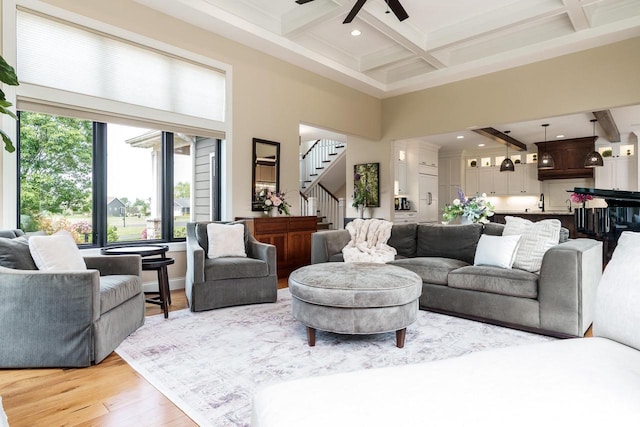1102 Eldon Way, Edgerton, WI 53534 - living area with stairway, a towering ceiling, beamed ceiling, a ceiling fan, and light wood-style floors