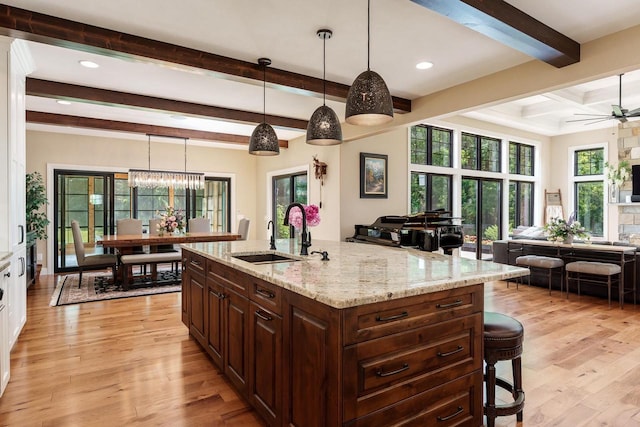 1102 Eldon Way, Edgerton, WI 53534 - kitchen with open floor plan, beam ceiling, light wood-style floors, light stone countertops, and a breakfast bar area