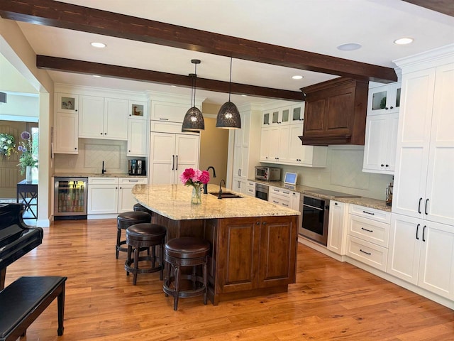 1102 Eldon Way, Edgerton, WI 53534 - kitchen featuring appliances with stainless steel finishes, wine cooler, a breakfast bar, light wood-type flooring, and decorative backsplash
