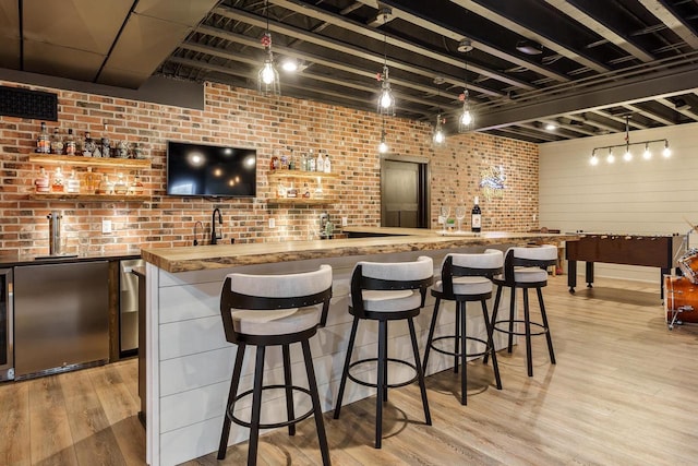 1102 Eldon Way, Edgerton, WI 53534 - indoor wet bar featuring refrigerator, brick wall, light wood-style flooring, and decorative light fixtures
