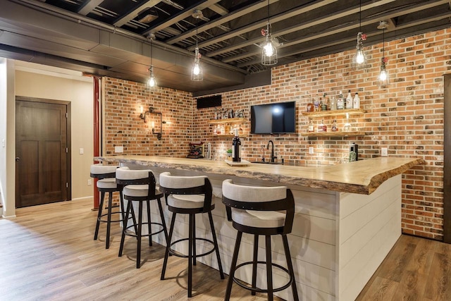 1102 Eldon Way, Edgerton, WI 53534 - indoor wet bar with brick wall, light wood finished floors, and pendant lighting