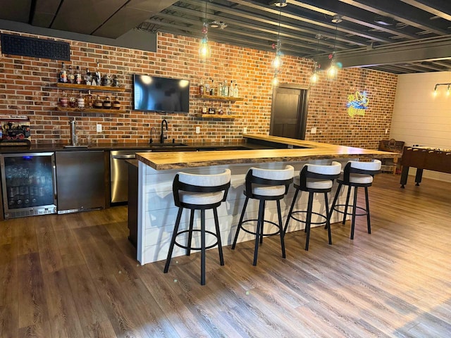 1102 Eldon Way, Edgerton, WI 53534 - indoor wet bar with beverage cooler, dark wood-style floors, decorative light fixtures, brick wall, and stainless steel dishwasher