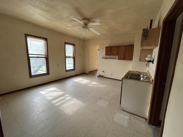 1218 W Locust St, Milwaukee, WI 53206 - kitchen with a sink, ceiling fan, baseboards, under cabinet range hood, and brown cabinets