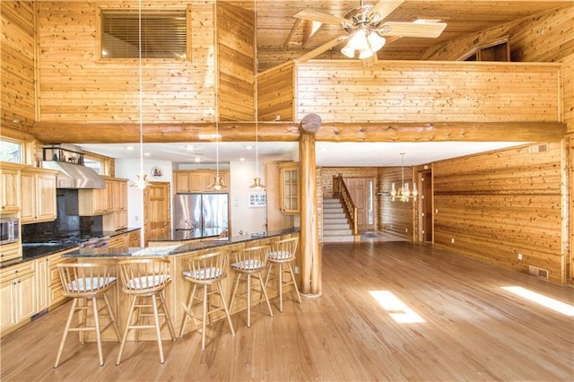 11053 N Robin Ln, Hayward, WI 54843 - kitchen featuring stainless steel appliances, wood walls, a breakfast bar area, a high ceiling, and dark countertops