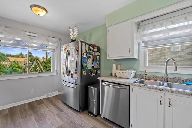 3433 Illinois St, Mount Pleasant, WI 53405 - kitchen featuring appliances with stainless steel finishes, a sink, light wood-style floors, and white cabinetry