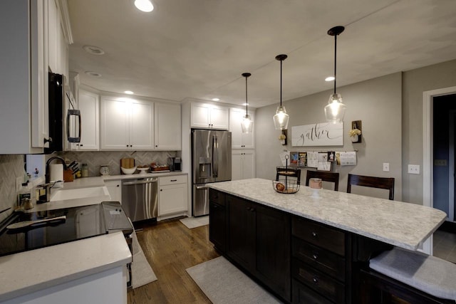 396 Panther Ct, Whitewater, WI 53190 - kitchen with appliances with stainless steel finishes, decorative backsplash, a sink, white cabinets, and a breakfast bar area