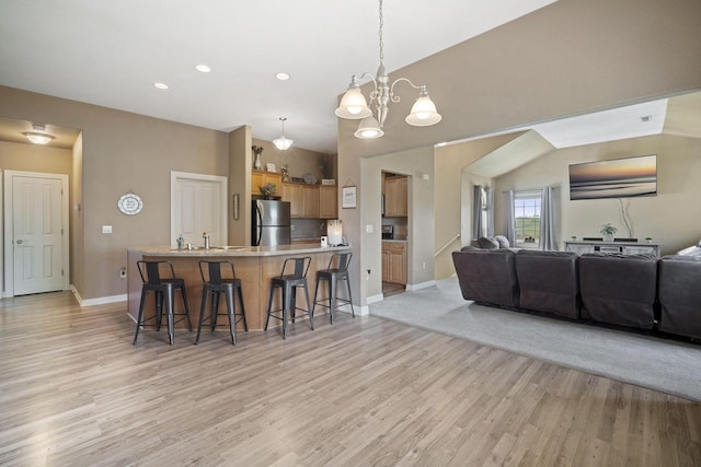 1820 Stoney Ln, Slinger, WI 53086 - kitchen featuring freestanding refrigerator, a kitchen bar, open floor plan, light wood finished floors, and baseboards