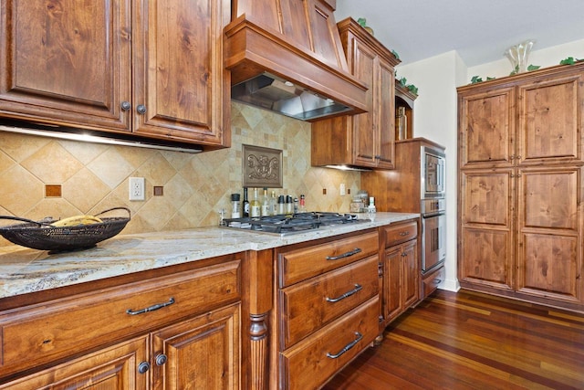 4205 Quarry Springs Dr, Racine, WI 53405 - kitchen with stainless steel appliances, brown cabinetry, premium range hood, dark wood-style floors, and light stone countertops