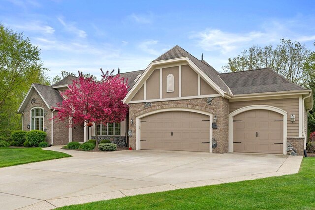 4205 Quarry Springs Dr, Racine, WI 53405 - tudor house featuring an attached garage, driveway, stone siding, and a shingled roof