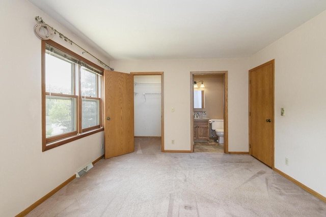 1915 Bonnie Ln, Waukesha, WI 53188 - unfurnished bedroom featuring light colored carpet, a walk in closet, a closet, connected bathroom, and baseboards