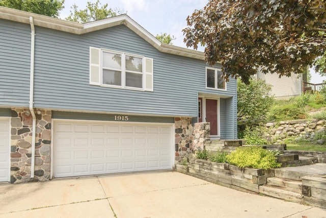 1915 Bonnie Ln, Waukesha, WI 53188 - view of front facade with stone siding, an attached garage, and driveway