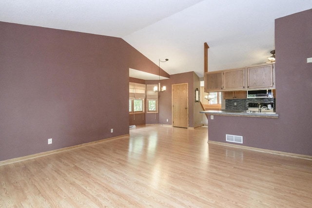1915 Bonnie Ln, Waukesha, WI 53188 - unfurnished living room featuring light wood-style flooring, a chandelier, baseboards, high vaulted ceiling, and ceiling fan