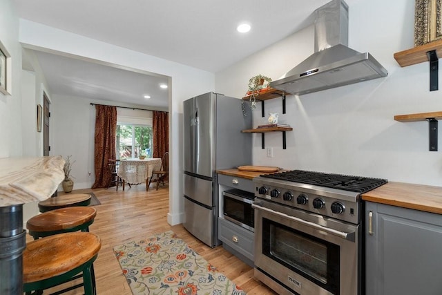 20454 70th Ave, Chippewa Falls, WI 54729 - kitchen with appliances with stainless steel finishes, wall chimney exhaust hood, gray cabinetry, wood counters, and open shelves