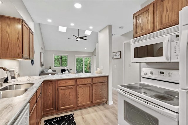 1109 Mckenna Blvd Unit G, Madison, WI 53719 - kitchen featuring white appliances, a skylight, light wood-style flooring, lofted ceiling, and brown cabinetry