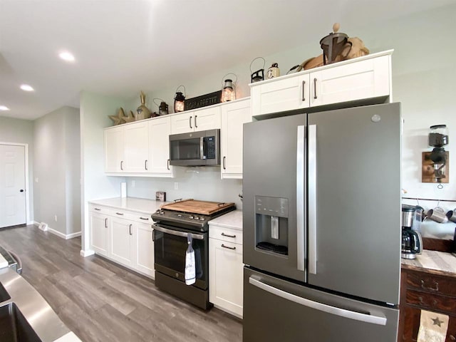 110 Grand St, Highland, WI 53543 - kitchen with appliances with stainless steel finishes, light countertops, wood finished floors, white cabinetry, and recessed lighting