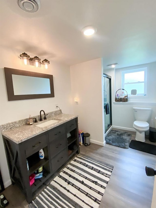 110 Grand St, Highland, WI 53543 - bathroom featuring toilet, a stall shower, vanity, wood finished floors, and baseboards