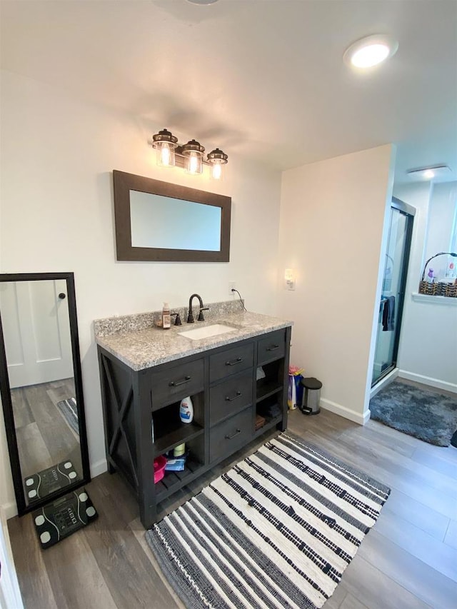 110 Grand St, Highland, WI 53543 - full bathroom featuring wood finished floors, vanity, a stall shower, and baseboards