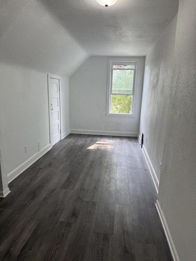 2667 N 36th St, Milwaukee, WI 53210 - additional living space with a textured ceiling, vaulted ceiling, dark wood-style floors, and baseboards