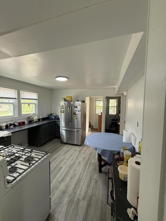 2667 N 36th St, Milwaukee, WI 53210 - kitchen with freestanding refrigerator, white range with gas stovetop, light wood-style floors, and dark countertops