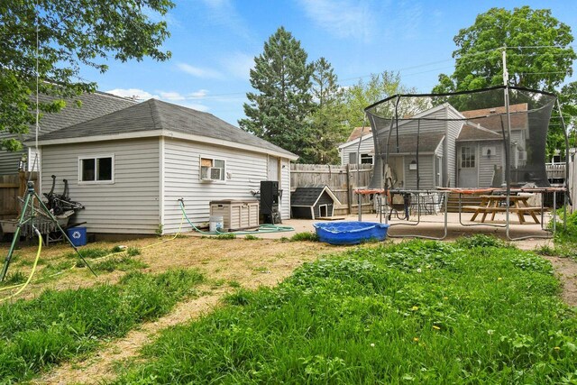324 N Lincoln Ave, Beaver Dam, WI 53916 - rear view of house with a trampoline, a fenced backyard, an outdoor structure, and a shingled roof