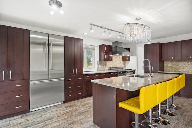 6650 N 114th St, Milwaukee, WI 53224 - kitchen with high end appliances, wall chimney range hood, light wood-type flooring, a kitchen breakfast bar, and a sink