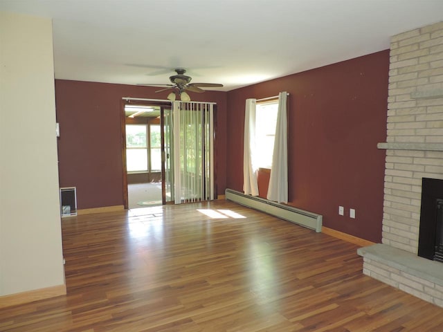 422 E Catherine St, Muscoda, WI 53573 - unfurnished living room featuring a baseboard radiator, a brick fireplace, a ceiling fan, wood finished floors, and baseboards