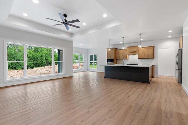 3566 W Hank Ave, De Pere, WI 54115 - unfurnished living room featuring a tray ceiling, light wood-type flooring, recessed lighting, baseboards, and ceiling fan