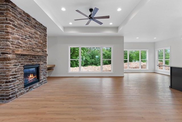 3566 W Hank Ave, De Pere, WI 54115 - unfurnished living room featuring wood finished floors, a raised ceiling, a stone fireplace, recessed lighting, and baseboards