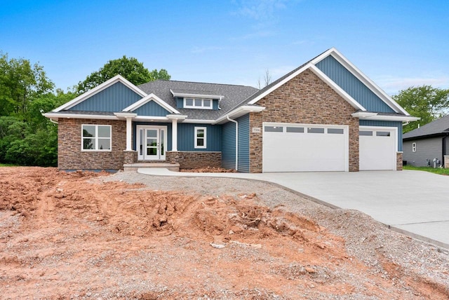 3566 W Hank Ave, De Pere, WI 54115 - craftsman house featuring stone siding, an attached garage, driveway, and board and batten siding
