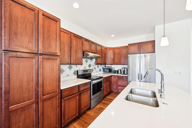 2418 Leopold Way, Sun Prairie, WI 53590 - kitchen featuring appliances with stainless steel finishes, under cabinet range hood, a sink, light countertops, and hanging light fixtures