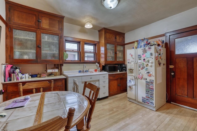1107 S 71st St Unit 1109, West Allis, WI 53214 - kitchen with white refrigerator with ice dispenser, stainless steel microwave, light countertops, light wood-type flooring, and glass insert cabinets