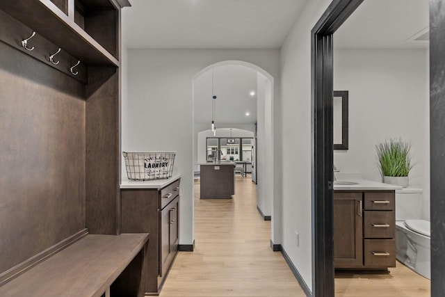 1338 Highland Ridge Dr, De Pere, WI 54115 - mudroom featuring light wood finished floors, arched walkways, a sink, and baseboards