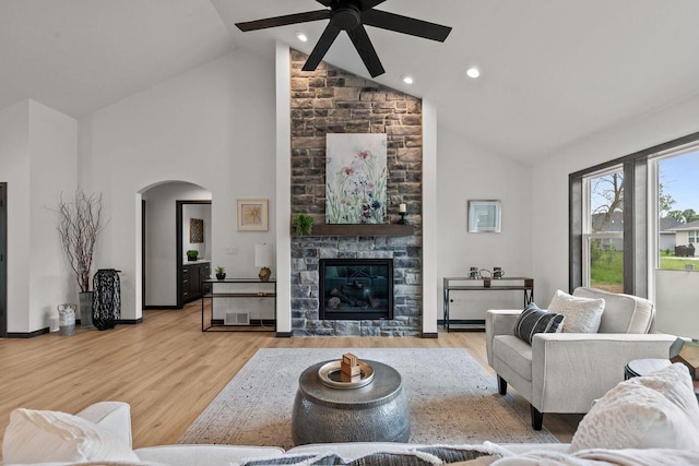 1338 Highland Ridge Dr, De Pere, WI 54115 - living room featuring ceiling fan, arched walkways, high vaulted ceiling, wood finished floors, and a stone fireplace