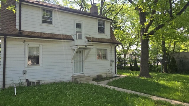 5415 N 36th St, Milwaukee, WI 53209 - back of house featuring entry steps, a chimney, a lawn, and roof with shingles