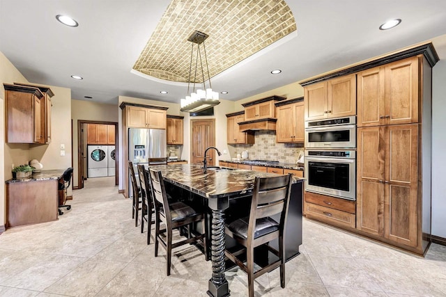 1830 Pine Tree Ct, Luxemburg, WI 54217 - kitchen featuring independent washer and dryer, a sink, stainless steel appliances, a tray ceiling, and a kitchen bar