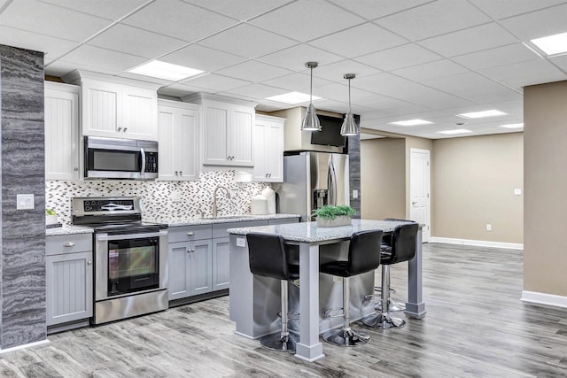 1830 Pine Tree Ct, Luxemburg, WI 54217 - kitchen featuring appliances with stainless steel finishes, a sink, a kitchen island, baseboards, and light wood-type flooring