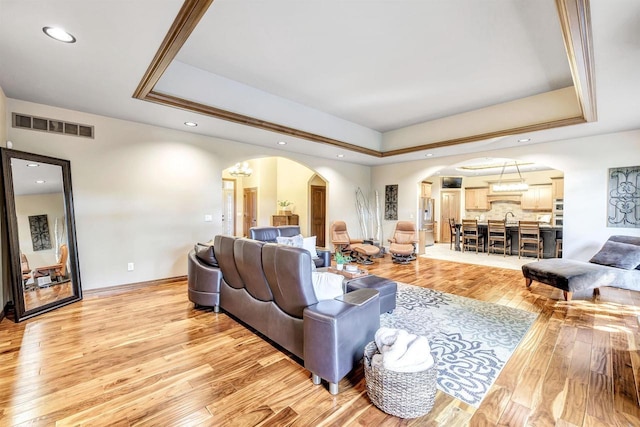 1830 Pine Tree Ct, Luxemburg, WI 54217 - living room with arched walkways, a raised ceiling, light wood-type flooring, recessed lighting, and baseboards