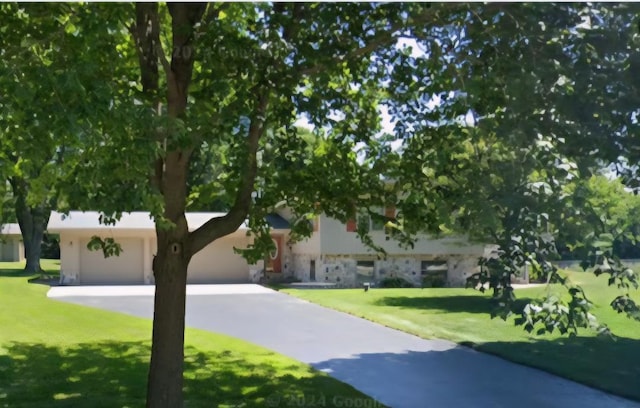 N9570 Sunset Dr, East Troy, WI 53120 - view of front of home featuring driveway, a front lawn, stone siding, and a garage