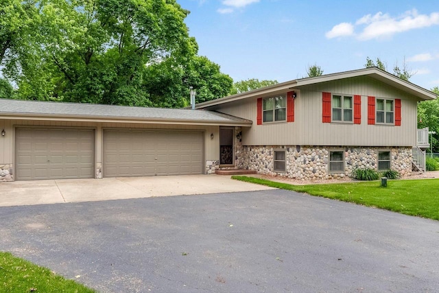 N9570 Sunset Dr, East Troy, WI 53120 - tri-level home featuring asphalt driveway, a garage, stone siding, and a front lawn