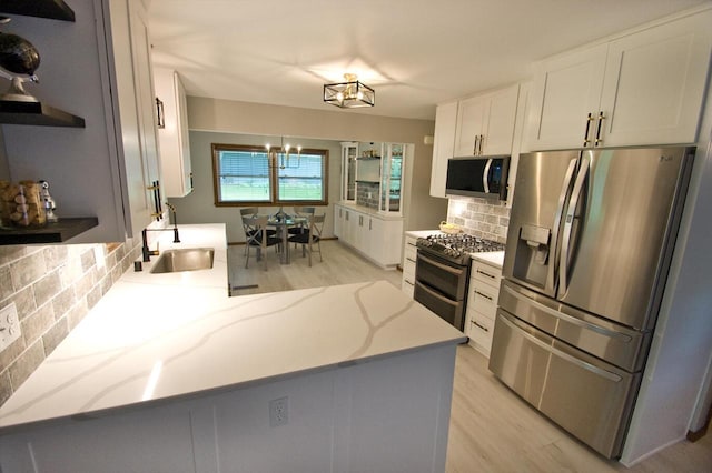 11426 W Woods Rd, Franklin, WI 53132 - kitchen featuring stainless steel appliances, a sink, backsplash, light wood finished floors, and white cabinetry