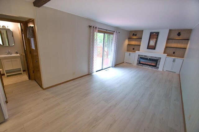 11426 W Woods Rd, Franklin, WI 53132 - unfurnished living room with a glass covered fireplace, light wood finished floors, a sink, and baseboards