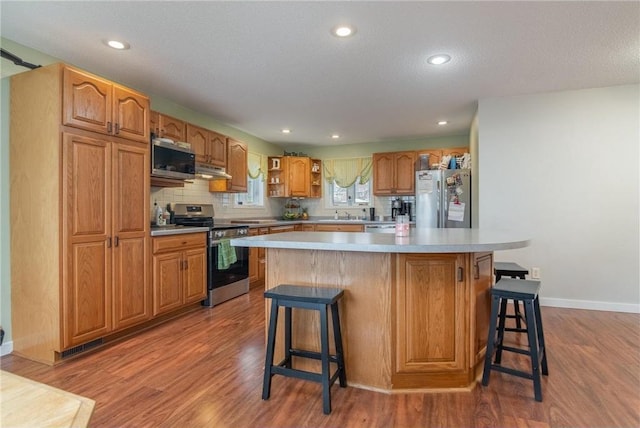 222 1st Ave, Clear Lake, WI 54005 - kitchen featuring appliances with stainless steel finishes, wood finished floors, open shelves, a breakfast bar, and recessed lighting