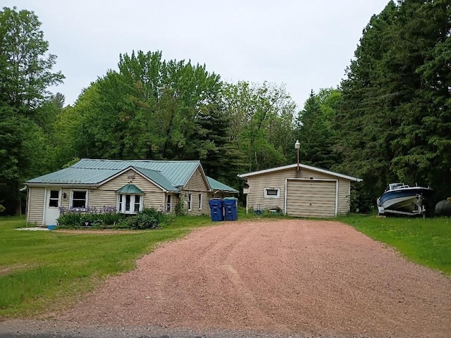 15380 Brandenburg Ave, Merrill, WI 54452 - view of front of home with driveway, an outdoor structure, a detached garage, metal roof, and a forest view