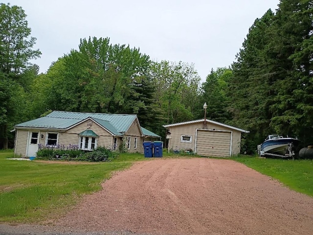 15380 Brandenburg Ave, Merrill, WI 54452 - view of front of home with dirt driveway, an outdoor structure, a detached garage, metal roof, and a front lawn