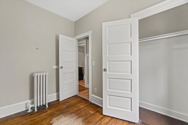 1718 W Washington St Unit 1720, Milwaukee, WI 53204 - unfurnished bedroom with radiator, dark wood-type flooring, baseboards, and a closet